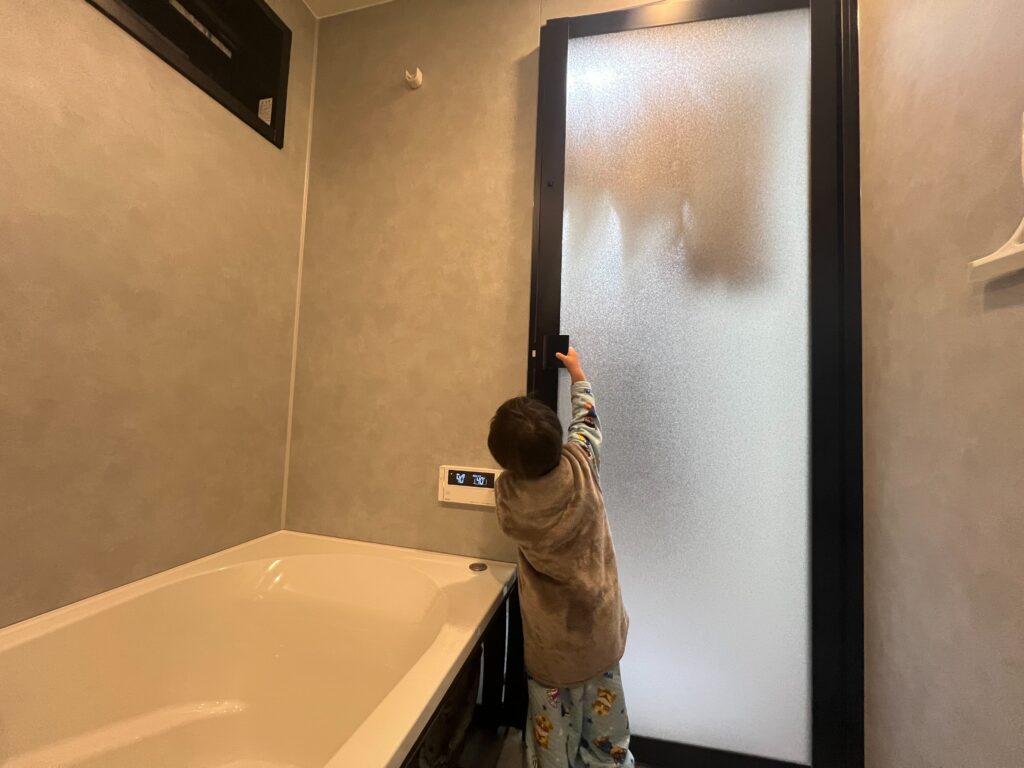 浴室の開き戸を開けようとする子供の写真画像